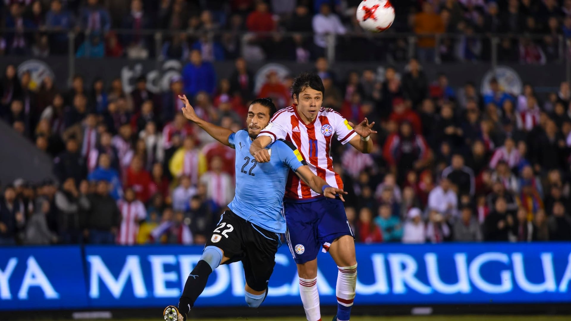 Uruguay's Martin Caceres (L) and Paraguay's Angel Romero jump for the ball