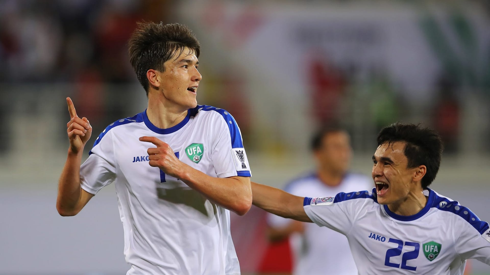 Eldor Shomurodov of Uzbekistan (14) celebrates with Javokhir Sidikov (22) as he scores his team's first goal